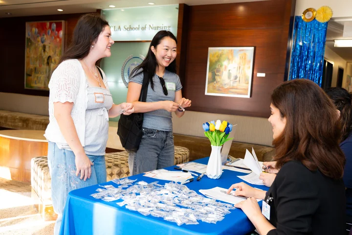 Two people at the table tending to two students standing up