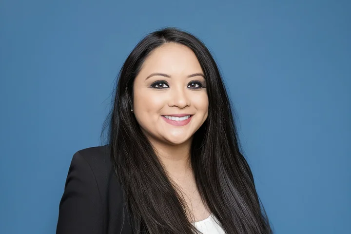 UCLA Nursing student Julie Bernardo in front of a blue background wearing a black jacket and white shirt.