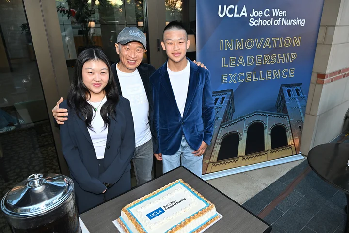 Joe C. Wen and two of his children with a cake with the new UCLA Joe C. Wen School of Nursing logo