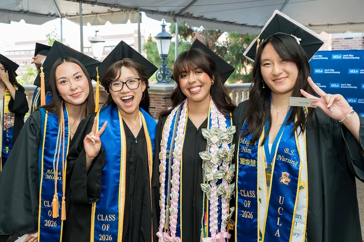 Four nursing students wearing their cap and gowns at the commencement ceremony.