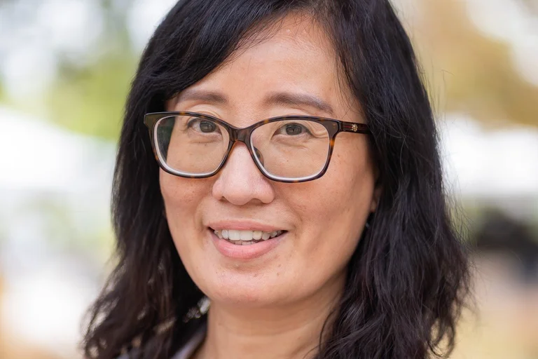 Dr. Suwen Pan wearing black shirt, white lab coat, and glasses.