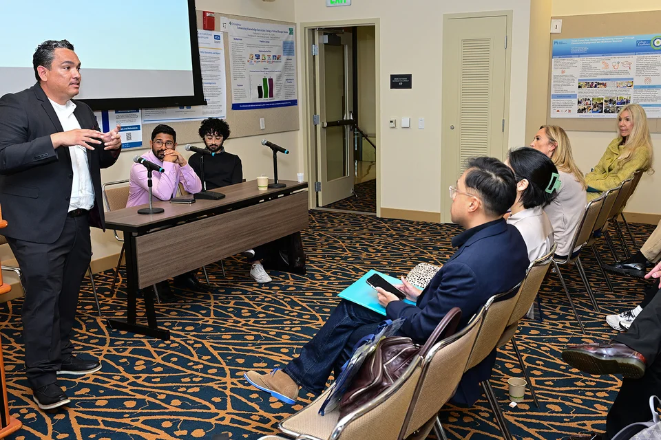 UCLA Nursing's Gerardo Flores presenting his research to a seated audience.