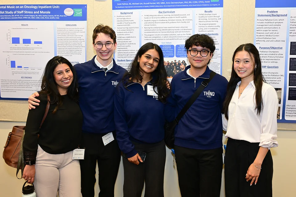 Five poster presenters posing for a photo with their posters behind them.