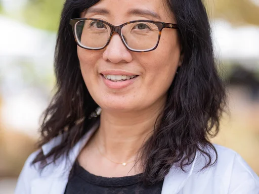 Dr. Suwen Pan wearing black shirt, white lab coat, and glasses.