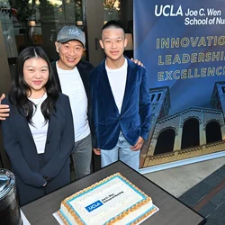 Joe C. Wen and two of his children with a cake with the new UCLA Joe C. Wen School of Nursing logo